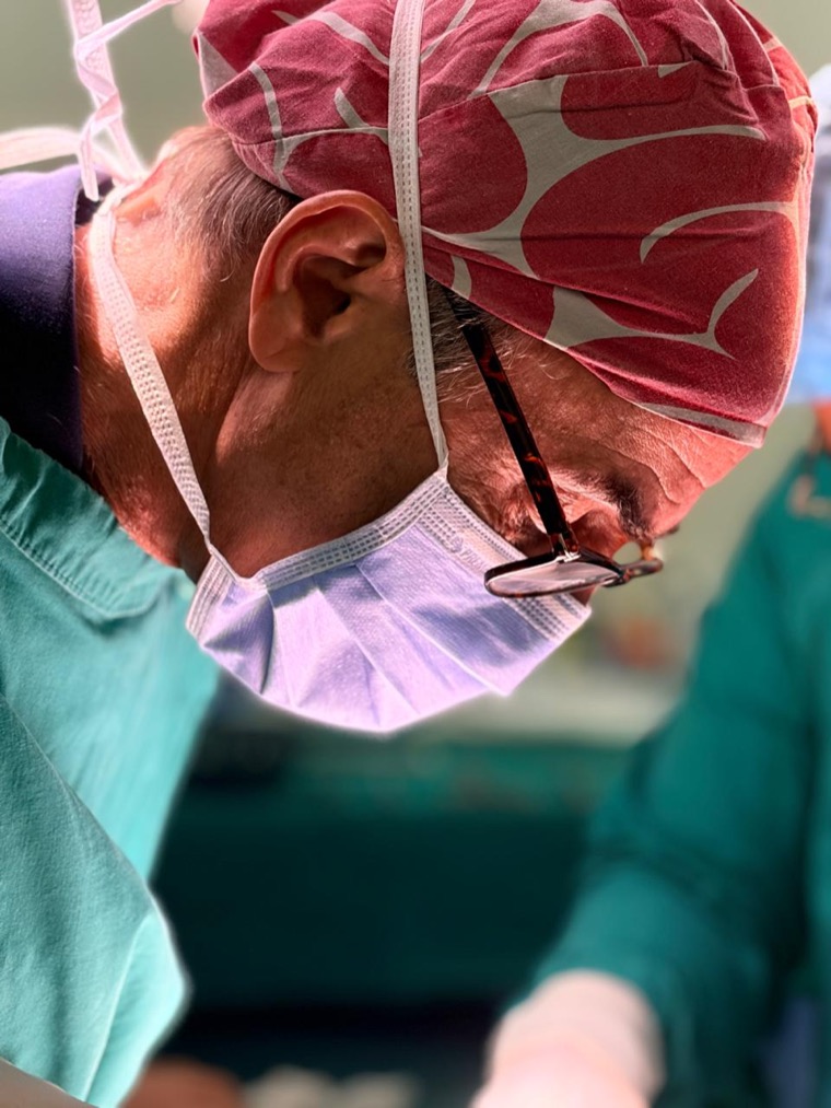 Prof Panieri in theatre wearing a patterned surgical cap and mask